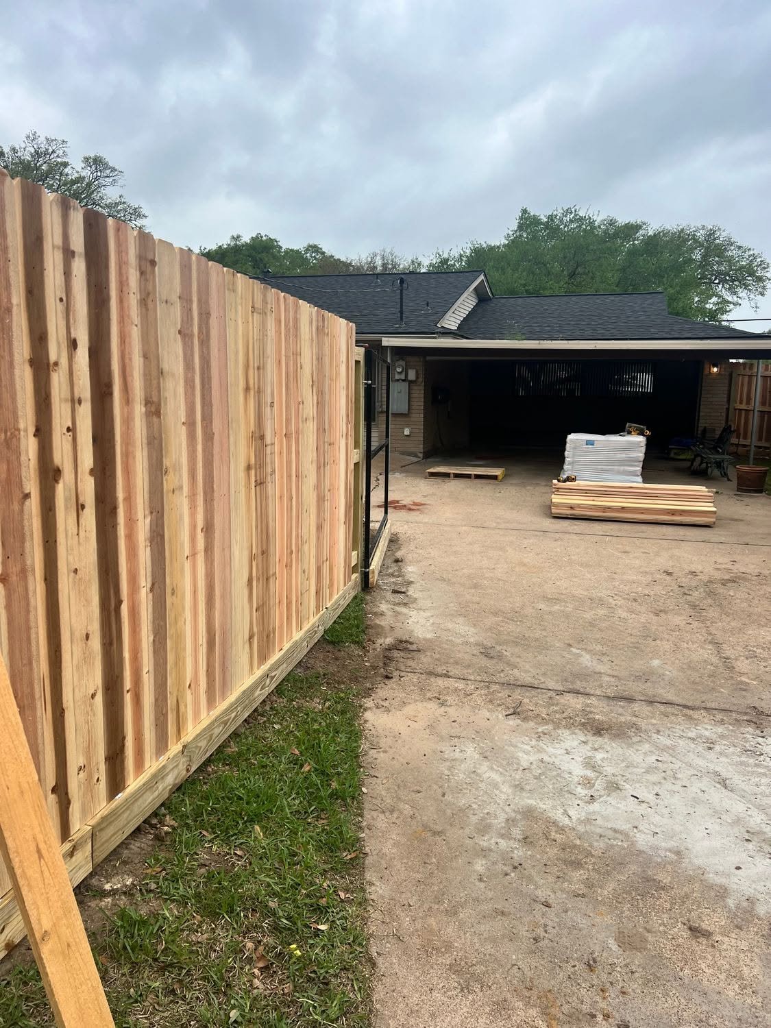 New wooden privacy fence alongside a dirt driveway — recent project by Pride of Texas Fence Company